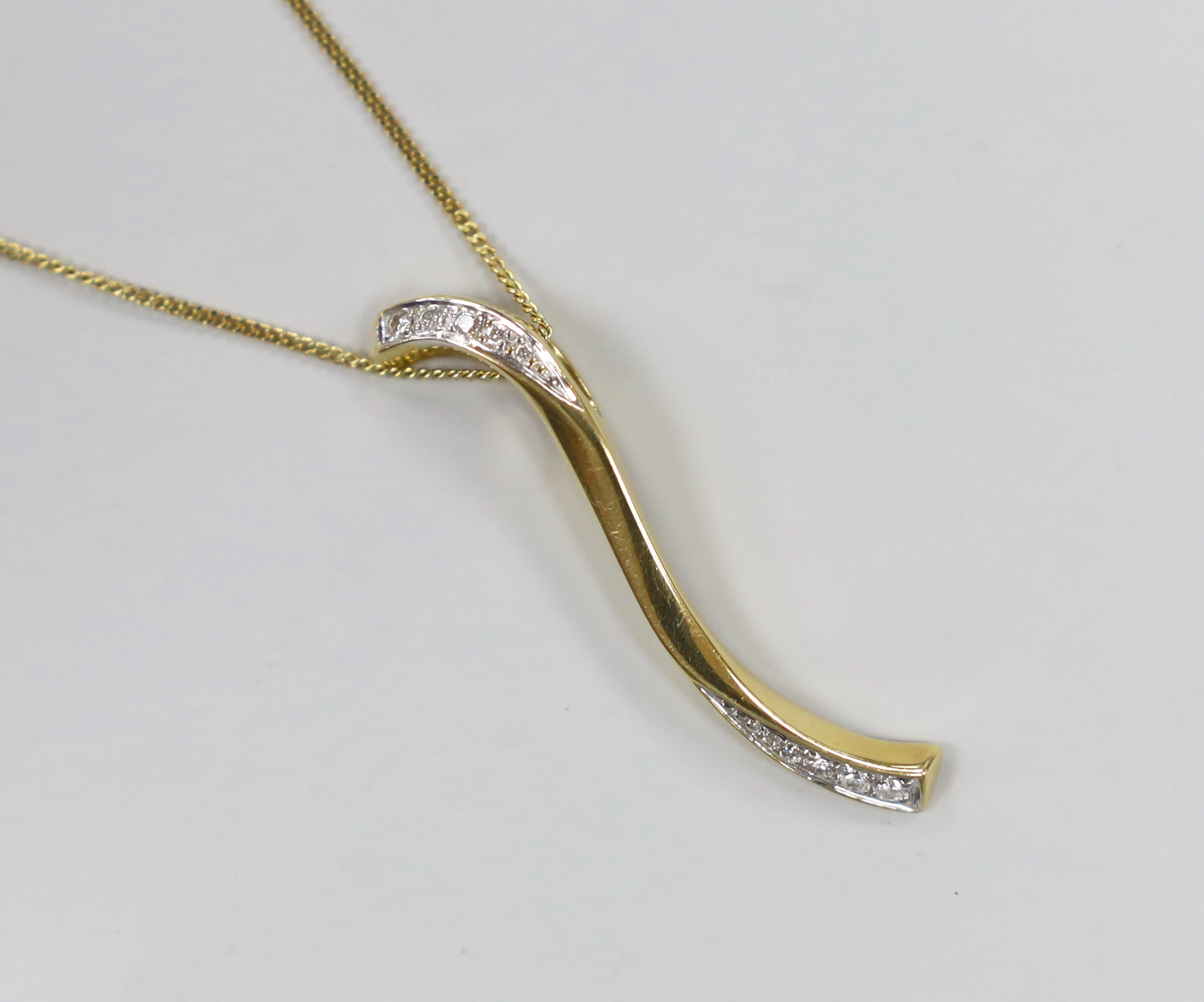 A modern 18ct gold and diamond chip 'S' shaped pendant, 38mm, on an 18ct gold chain, 39cm, gross weight 5.3 grams.